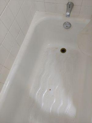 Dirty tub with rust stains and peeling paint.