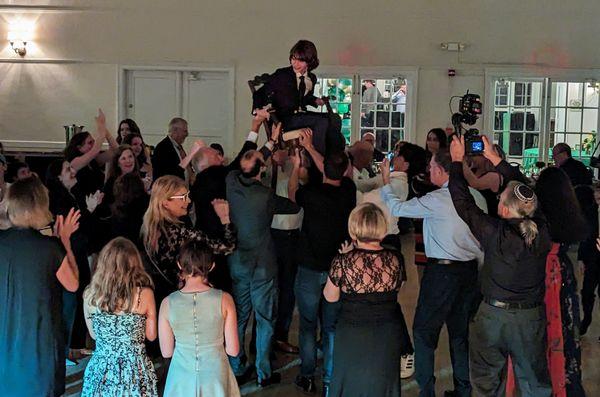 Bar mitzvah boy up in a chair during the horas.