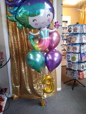 This is a bouquet we did for a 3 year old. We love how the chrome balloons pair so well with the mermaid.