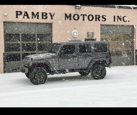 Snow falling on a 17 Jeep Wrangler Unlimited outside of the Auto Body Shop.