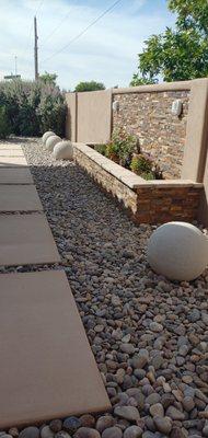 Large river rocks, concrete slabs. Flower box with deco stones. Concrete pavers as a design element.