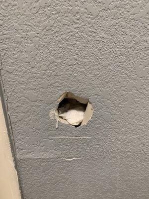 Hole in wall behind door to bathroom