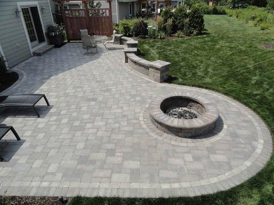 Large outdoor brick patio with a fire pit, dining area and lounging area.