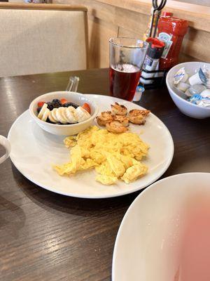 Fruit bowl, scrambled eggs and grilled shrimps