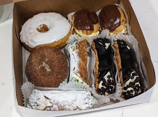 Glazed donut, apple donut, eclairs, chocolate chip cannoli, and pistachio cream cannoli