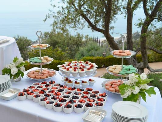 Dessert station with french macarons, fresh berry cups, and miniature creme brulees overlooking the ocean in Laguna Beach