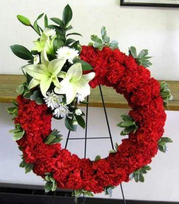 A gorgeous sympathy wreath of red carnations and white lily accents.