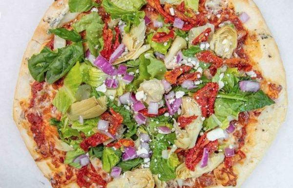 VEGGIE PIZZA with marinara sauce, garlic, cream cheese, green peppers, sun-dried tomatoes, red onions, chopped romaine, and mozzarella.