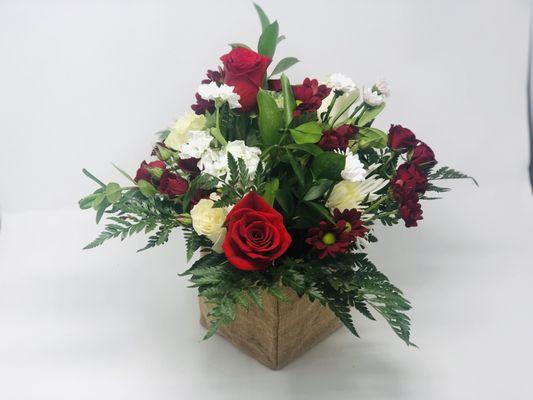 Roses and Christmas greens in a cube vase