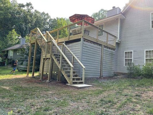 Custom-built deck with custom railings, complete with a staircase with a landing and concrete slab at the bottom.