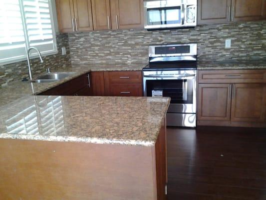 Kitchen cabinets with Granite counter tops, linear glass backsplash. And stainless steel appliances.