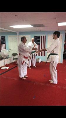 Student accepting new belt ranking from Master Kyoshi