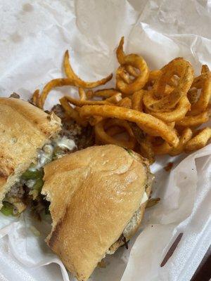 Delicious Philly cheesesteak sandwich with curly fries