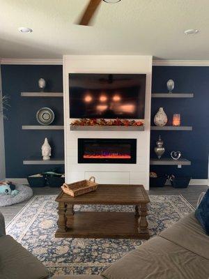 Complete entertainment wall with build-in electric fireplace and custom floating shelving