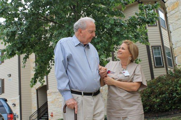 Caring Senior Service caregiver helping a client walk