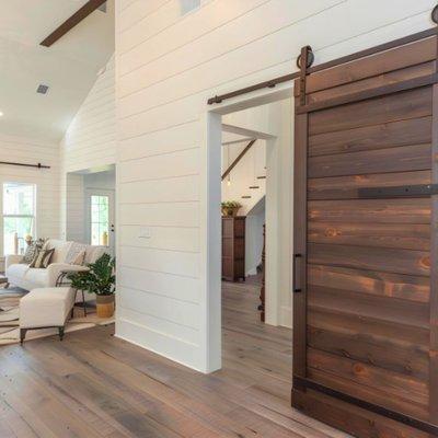 Modern farmhouse interior featuring a striking wooden sliding barn door, elegantly contrasting with the bright, airy shiplap walls.