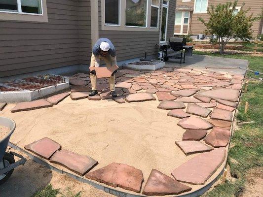 Our workers Zack placing a small patio made from sand and flat stone