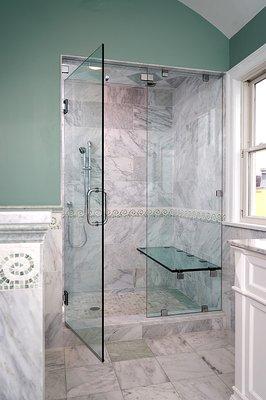 Frameless steam shower enclosure with custom glass seat