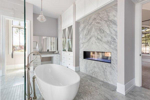 Contemporary gray and white bathroom with floating fireplace.