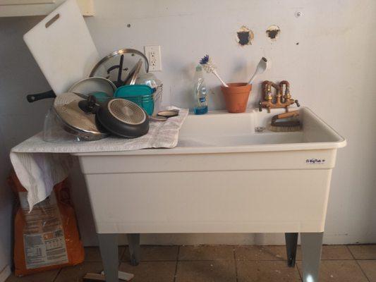 Utility tub, spigots and shelf removed, awaiting arrival of base cabinets, regular sink, and dishwasher.  2x2 tile for "countertop"