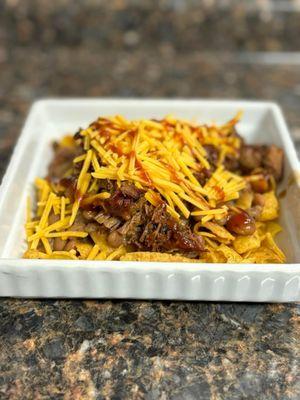 Frito Pie! Fritos topped with our Housemade Savory Beans, meat of your choice, cheese, sauce and sour cream. Sooooo good!