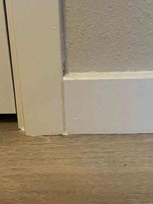 caulking between a door frame baseboard, sloppily done