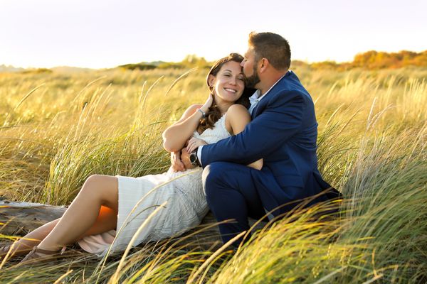 Couples photographer engagement photography love photos in Portsmouth New Hampshire. couple sitting in tall grass together hugging