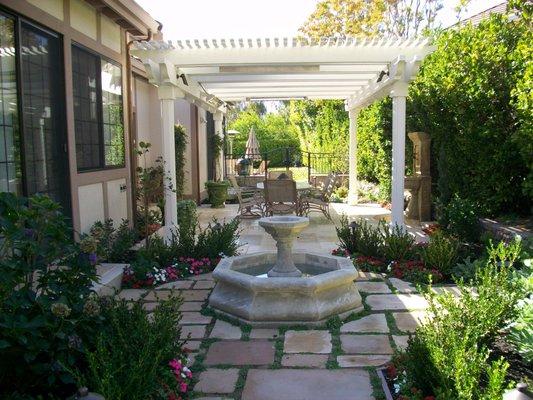 Hand carved Fence Limestone Fountain, flagstone & Isotama moss with a  Al fresco dining room with shade trellis.