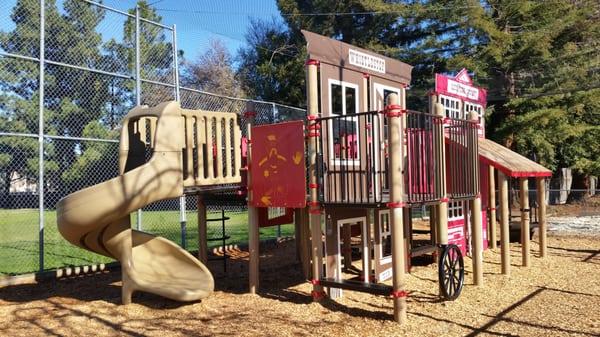 Cute old west themed playground structure next to a baseball field. Sandbox, no swings.