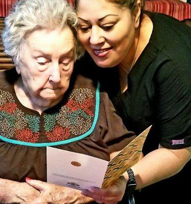 100 year-old, Miss Betty being read a card from a friend by her attendant Maria.