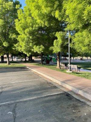 View from parking of nature trees, benches and sidewalk surrounding Nisson Park