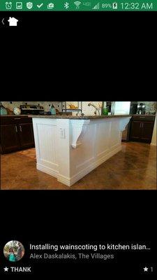 Kitchen island covered with wainscoting, various size trim boards and cornices.