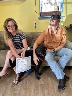 Izzy, a black Labrador Retriever mix graduating from board and train.