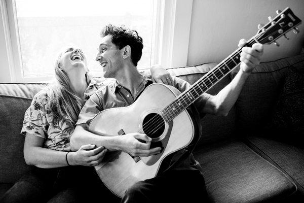 Engaged couple laughing together with guitar