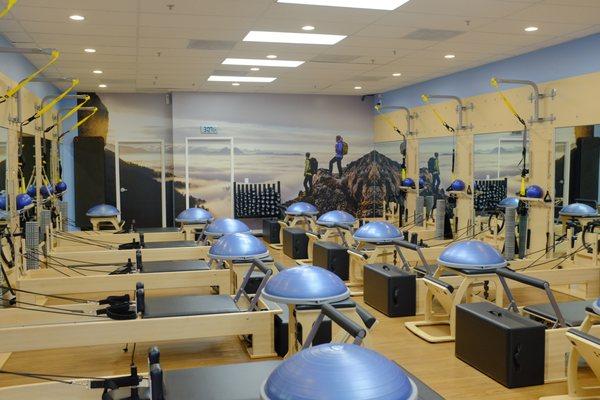 Workout area with reformers, EXO chairs, TRX suspension systems, BOSU balls, springboards, and ballet barre.