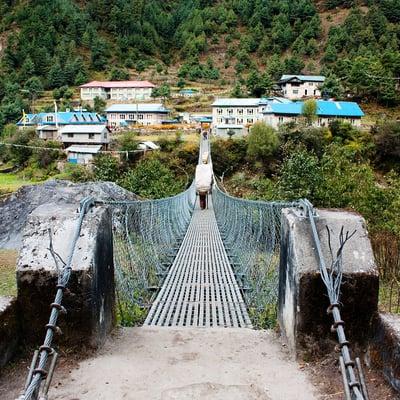 Porters crossing a suspension bridge at Phakdingma, on the way to Everest Base Camp