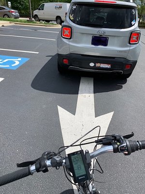 Line to drive thru. Even the arrow is in the wrong direction! there are five cars ahead. Use your coconut when you design a parking lot