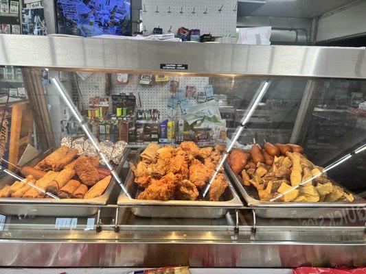 Crispitos are on the left in front of the foil. Fried chicken, egg rolls, corn dogs, and jojos also pictured.