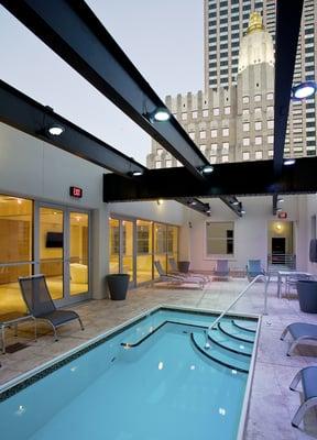 The pool deck features an open-roof and views of the building tops.  A publically available grill and outdoor TV are featured in this space.