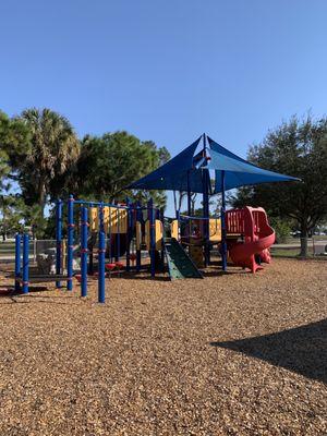 Partially cover playground equipment with wood chips to keep kids safe and its fenced in.