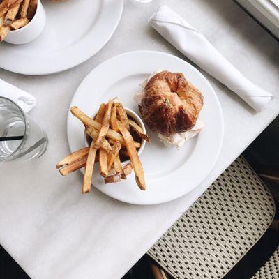 Turkey & avocado inside a croissant with a side of fries.