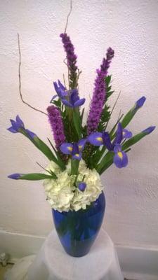 white hydrangea with blue iris and liatris in a blue vase.