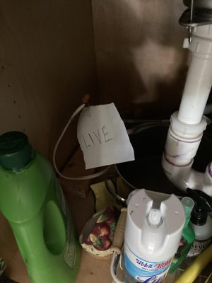 Exposed live electrical wires under the sink where the garbage disposal should have been reinstalled