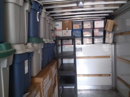 The inside of a truck being loaded with boxes,crates and Shelf's.