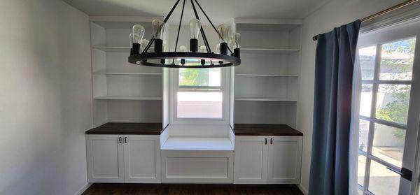 Cabinet and shelves combined with bench under window.