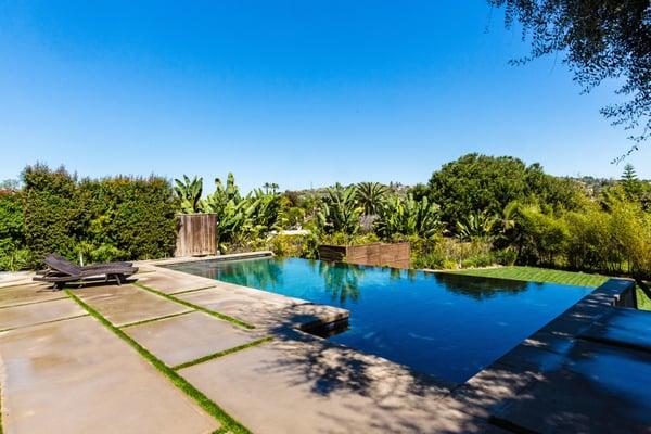 Infinity edge pool with concrete steppers and artificial grass.