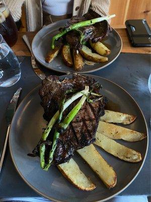 Porterhouse steak with potatoes, scallion and broccoli which is hiding underneath the steak