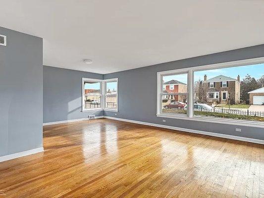 Large living room windows for tons of natural lighting and radiant wood floors stained and restored to its original beauty.