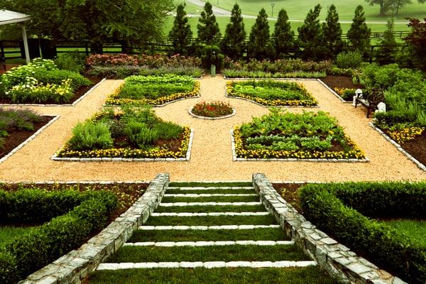 A formal boxwood parterre garden with pea gravel outline and turf/granite steps