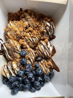 Cream puffs drizzled with milk, dark, white chocolate and cookie butter crumble.